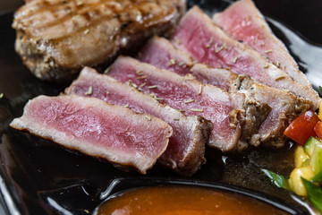Close Up Still Life of Roasted Tuna Steaks Crusted with Herbs and Sesame Seeds on Dark Gray Surface