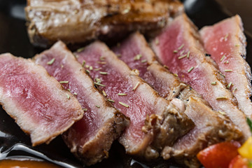 Close Up Still Life of Roasted Tuna Steaks Crusted with Herbs and Sesame Seeds on Dark Gray Surface