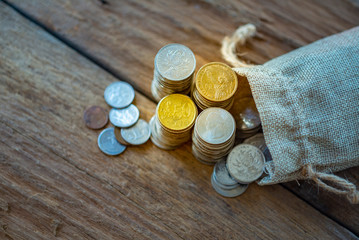 Us dollar,  euro and chinese yuan coins in sack and stacked, lay on real wooden plank.