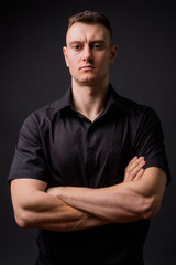 Obraz premium Young handsome businessman with arms crossed against gray background