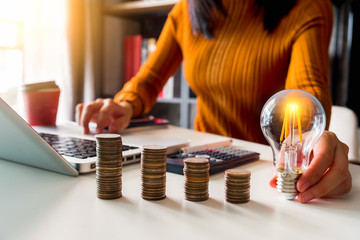 businesswoman hand holding lightbulb with saving money in office. 