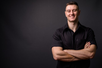 Portrait of young confident businessman smiling with arms crossed looking at camera