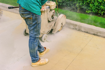 Male workers cutting concrete road surfaces to repair damaged roads.