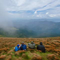 Group of tourist having rest after hiking and sitting on hill
