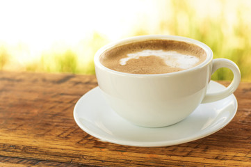 Latte Coffee in white cup on wooden table with morning light