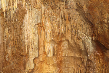 wonderful natural cave with fox-colored walls and formations of stalactites within, natural texture photo.