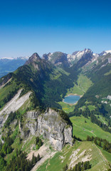 mountain landcape in the Alpstein region of Switzerland with jagged peaks and a pristine blue mountain lake in the valley far below