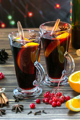 Christmas mulled red wine with spices and fruits on a wooden table. Traditional hot drink at New Year and Christmas time. Vertical Picture.