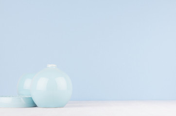Elegant modern home decor of smooth ceramic circle vase and bowl on white wood table and light blue wall.