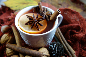 A hot drink with spices wrapped in a woolen shawl. Selective focus.Still life, food and drink, seasonal and holidays

