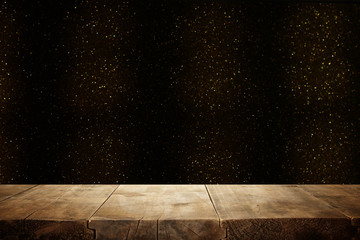 rustic wooden table in front of glitter black and gold bright bokeh lights.