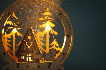 Low key Image of magical christmas scene of wooden pine forest, hut and santa claus over sleigh with deers.
