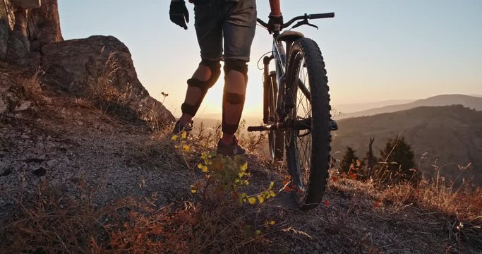Cool mountain biker standing on edge of a mountain, ready to ride down - recreational pursuit, getting away from it all 4k