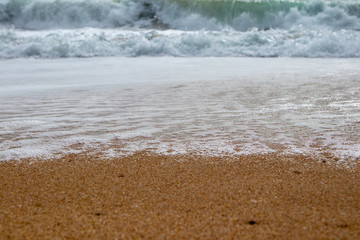 Close up of foamy wave on beach sand surface