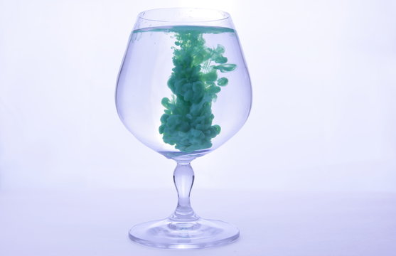 Green Paint In Water In A Crystal Glass On A White Background