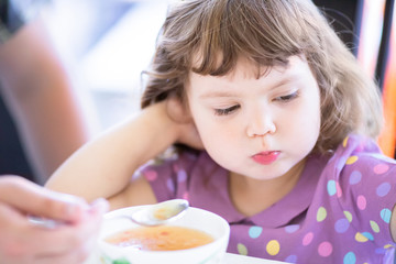Obraz na płótnie Canvas Cute little girl doesn't want to eat. Kid refusing food. Sad child