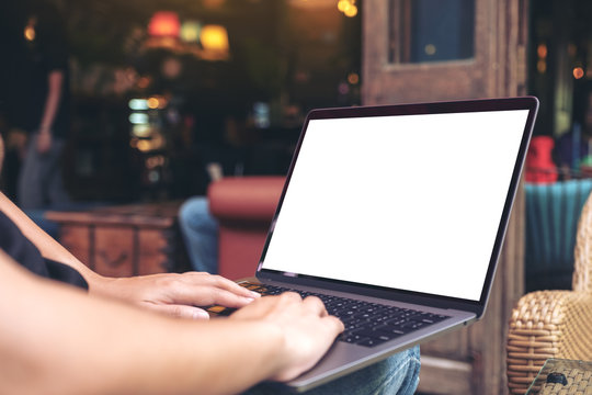 Mockup image of hands using and typing on laptop with blank white desktop screen while sitting outdoor