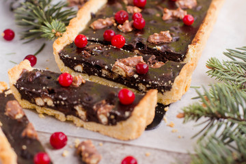 Chocolate tart with cranberries for Christmas holiday on gray table background.