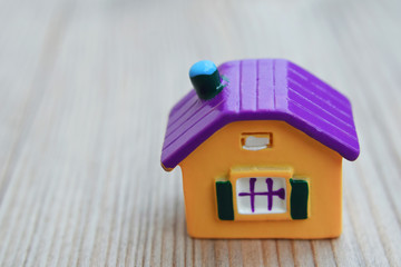 Colorful yellow house model on natural blurred wooden table background closeup view.  House building, loan, buying renting new home, real estate insurance concept.