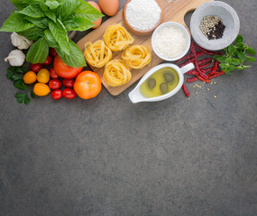 Italian food background, with tomatoes, basil, spaghetti, olives, parmesan, olive oil, garlic, peppercorns, parsley and chili. Copy Space. From top view