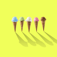 Variety of ice cream flavor in cones blueberry ,strawberry, green tea, chocolate and coconut setup on yellow background . Summer and Sweet menu concept.