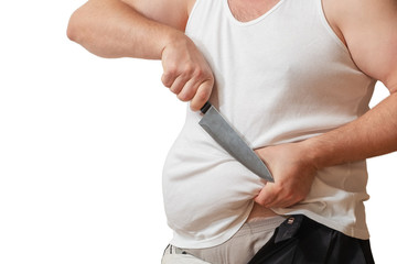 A man with one hand holds the fat fold on his big belly, and in the other hand holds a knife.