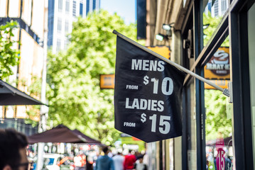 A sign with mens and ladies hair cut prices on a city street in Melbourne Australia
