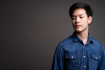 Young handsome Asian man wearing denim shirt