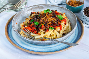 Kushari - Egyptian vegetarian dish with lentils, spiced tomato sauce and macaroni topped with fried onions
