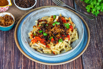Kushari - Egyptian vegetarian dish with lentils, spiced tomato sauce and macaroni topped with fried onions