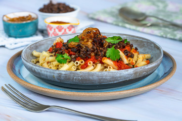 Kushari - Egyptian vegetarian dish with lentils, spiced tomato sauce and macaroni topped with fried onions