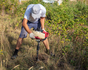 Worker drills the ground for the fence
