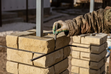 The worker is laying bricks on the fence