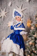 Fototapeta na wymiar Russian Snow Maiden (Grandfather of Santa Claus) in the New Year's interior near the Christmas tree. Waiting for New Year and Christmas