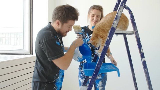 The concept of new real estate. Young couple with cat painting and renovation a room in their new house