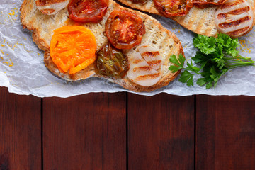 Toast with grilled vegetables. Vegetarian food. Red and yellow tomatoes. Grilled sandwich with tomatoes, onions and herbs. Bread with vegetables and honey. Vegan toast on wooden background