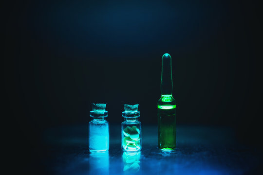 Unmarked glass chemical bottles filled with yellow chemical solution such as illegal sports performance enhancing anabolic steroids. artistic dark filter. low key photo