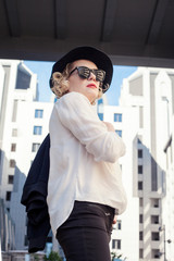 Fototapeta premium Beautiful blonde in a hat and with red lipstick on the street