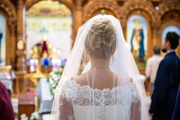 Bride and groom stand with crowns during the ceremony in church