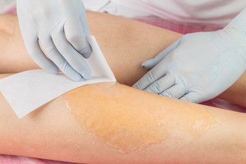 Obraz na płótnie Canvas Removing unnecessary hair on the legs. Procedure sugaring in a beauty salon.Depilatory sugar paste