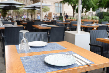 Table prepared on a restaurant sunny outdoor terrace with plates, wine cup and cutlery