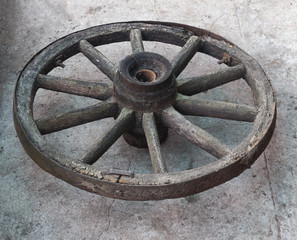 Old wooden wheel from a horse-drawn carriage on a concrete background, close-up, wooden wheel