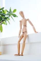 A wooden mannequin sits thoughtfully at the window.