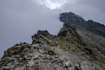 peak of Rysy mountain covered in mist. autumn ascent on hiking trails