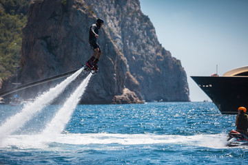 Flyboarding and seariding on the Sea near the mountain island. Water summer extreme sports.