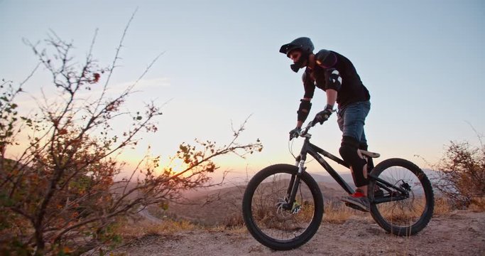Mountain cycler riding up the path in mountains in sunset, following the trail or road - extreme, fitness, 4k