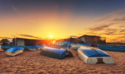 boats lie on the beach upside down at beautiful sunset