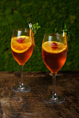 Two glasses of red cocktail with orange slice and cherry