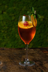 Glass of red cocktail with orange slice and cherry