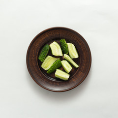 sliced cucumber in plate on white background top view